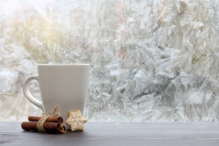 白色陶瓷杯与胡萝卜在窗口的背景下的雪花的形式是冻结美味的冬天心情