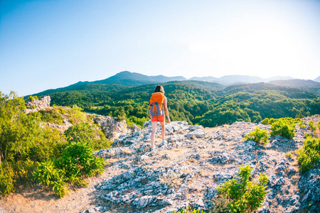 一个背着背包的女人沿着一条山路走.爬上山顶.旅行到风景如画的地方.