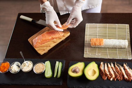 特写 viev 厨师手准备日本料理。厨师制作寿司卷在餐馆与许多成分在黑石板材