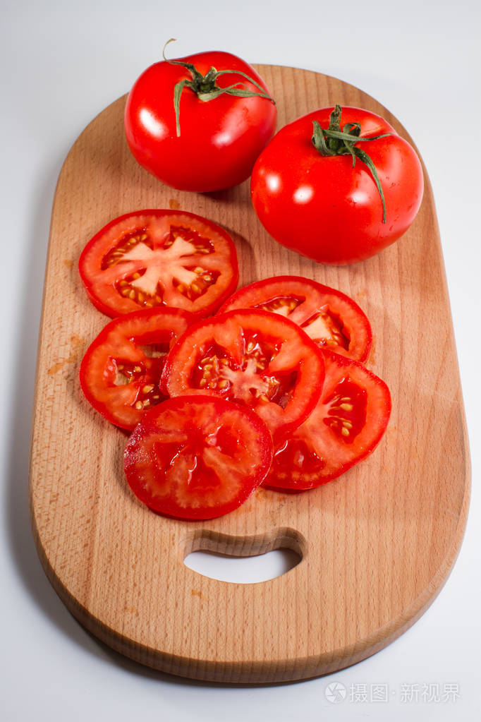 在白色背景上的案板上的全切片新鲜西红柿