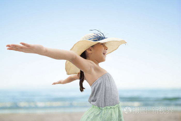 张开双臂拥抱在海滩的小女孩