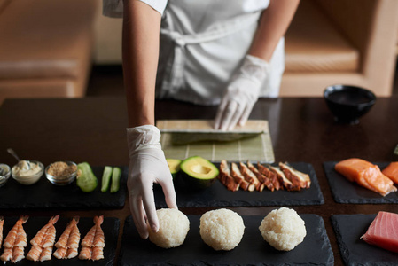餐厅餐饮寿司加工过程的特写视图。厨师正在为轧辊准备配料