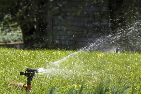 在炎热的夏日里, 草坪上的洒水水灌溉.复制空间照片