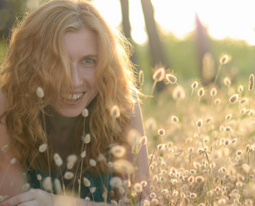 一个漂亮的红发笑的女孩在草丛里的肖像