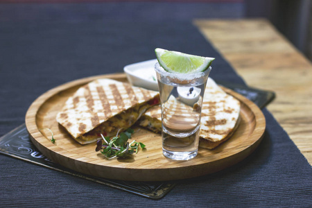 杯龙舌兰酒与石灰和部分 quesadilla 在圆木板, 墨西哥菜, 选择性重点