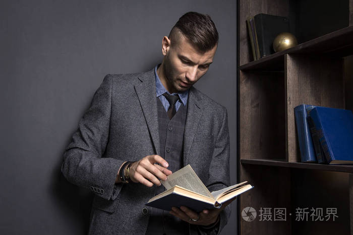穿着西装的有魅力的人看书。律师在他的办公室里保存着目录。用书学习人。自信的人在图书馆