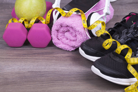 健身理念与手机和耳机, 重量, 毛巾, 苹果和运动鞋的木制背景