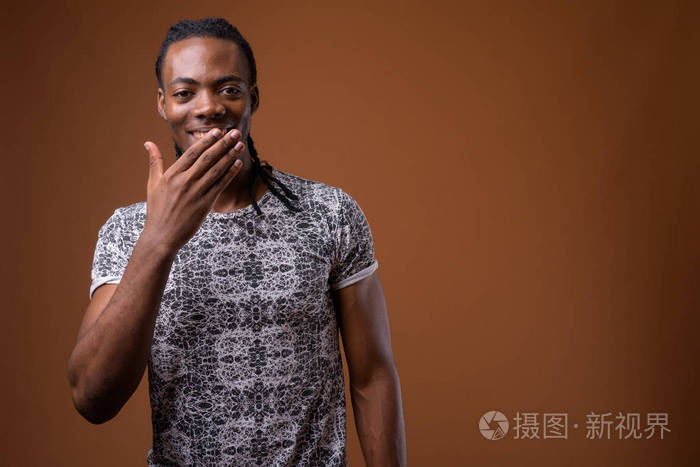 年轻英俊的非洲人反对褐色背景