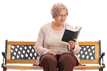 老妇人坐在长椅上看书, 在白色背景下阅读一本书。