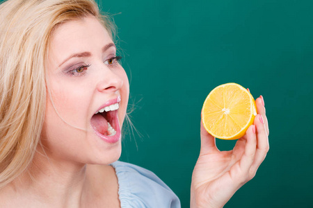 健康的饮食，刷新富含维生素的食物。女人抱着酸味的柑橘果实柠檬的嘴巴张开