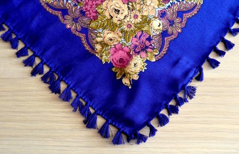 明亮的蓝色围巾与流苏和花卉图案在光的背景下