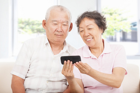 看着智能手机看着智能手机的快乐老人照片