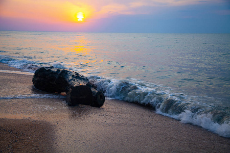 日落时美丽的大海。在黄色的太阳背景下喷洒和石头。海景