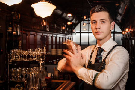 年轻英俊的酒保摇晃一个清新可口的夏季鸡尾酒在酒吧的背景下, 餐厅