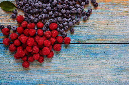 视图从上面的木桌表面只收集最大的新鲜覆盆子和蓝莓