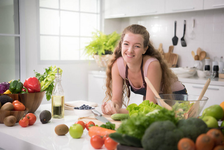 健康的年轻妇女在厨房准备健康的膳食和沙拉蔬菜