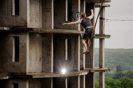 一个年轻勇敢的人的背影走在 slackline 的背景下高空建筑