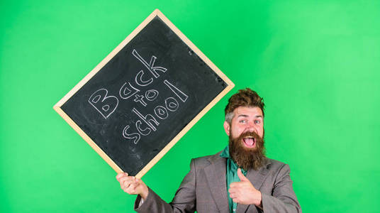邀请庆祝知识日。老师胡子人拿着黑板与题字回到学校绿色背景。老师愉快愉快的祝贺以开始新的学年
