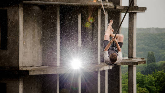 slackline 的年轻人和勇敢的人在雨天的高空建筑背景下的平衡