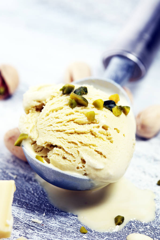 开心果冰淇淋勺与碎坚果和白色巧克力在一个质朴的背景