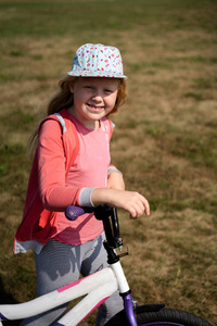 现代儿童的积极生活方式漂亮的金发女孩漫步在田野上的自行车