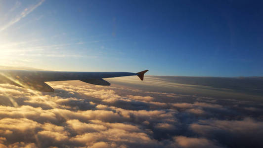机翼的飞机在日落与云彩。旅行, 冒险, 交通概念。日落时从机翼窗口观看