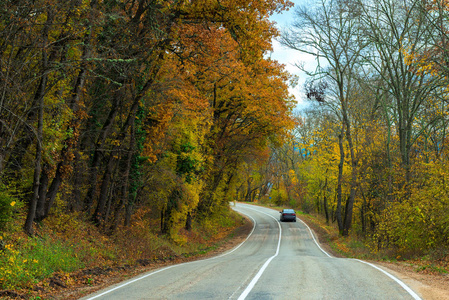 在秋天的午后, 汽车沿着蜿蜒曲折的道路前行