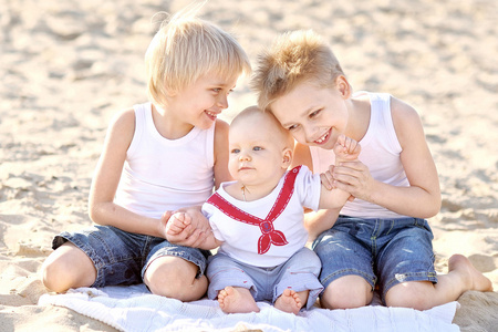 三个小男孩在夏天的海滩上的肖像照片