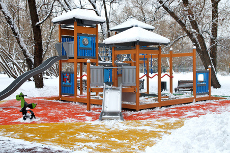 在第一场雪下的公园里的儿童游乐场