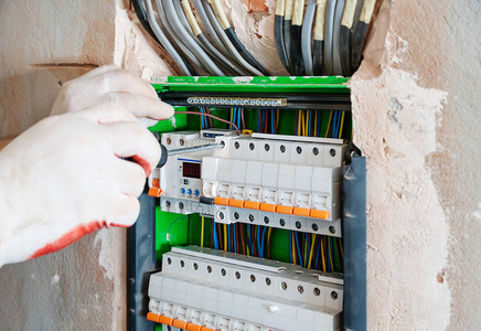 电工正在开关盒中安装保险丝照片