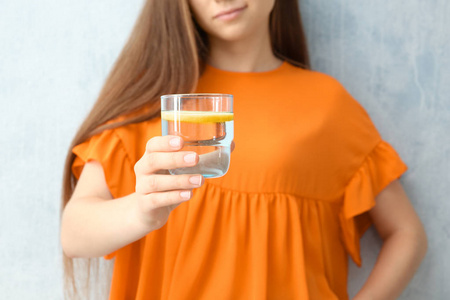 年轻妇女拿着玻璃柠檬水在颜色背景, 特写