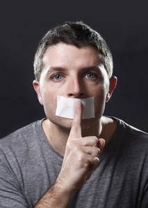 恐怖的脸和密封年轻英俊男子嘴上胶带密封以防止他说话照片