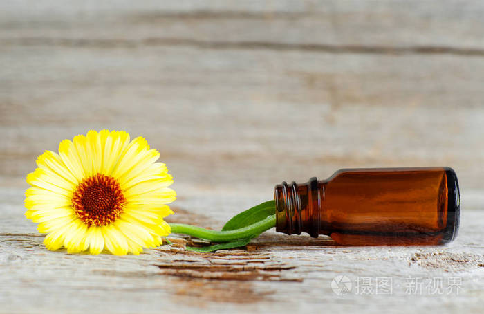 小玻璃瓶上的旧木制背景和金盏花 田间万寿菊 花, 合上。芳香疗法, 水疗和草药成分。复制空间