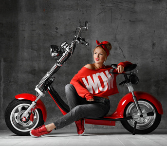妇女坐在摩托车摩托车复古推迟样式红色衬衫和牛仔裤