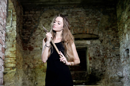 废墟中的女人手里拿着一把斧头。黑礼服的女性模型在废墟, 老宫殿在波兰
