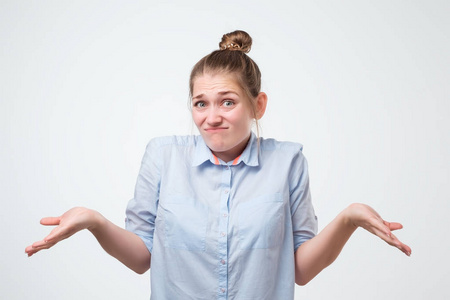 耸耸肩的欧洲女人穿着蓝色的衬衫, 疑惑地耸耸肩.
