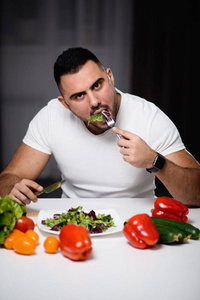 美丽的运动男子在家里吃健康的素食。健康生活方式的概念