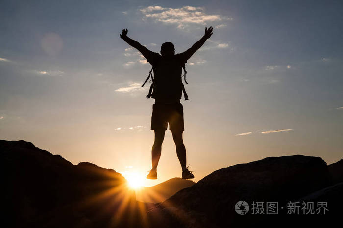夕阳下登山者徒步旅行的剪影.自由,风险,挑战,成功理念
