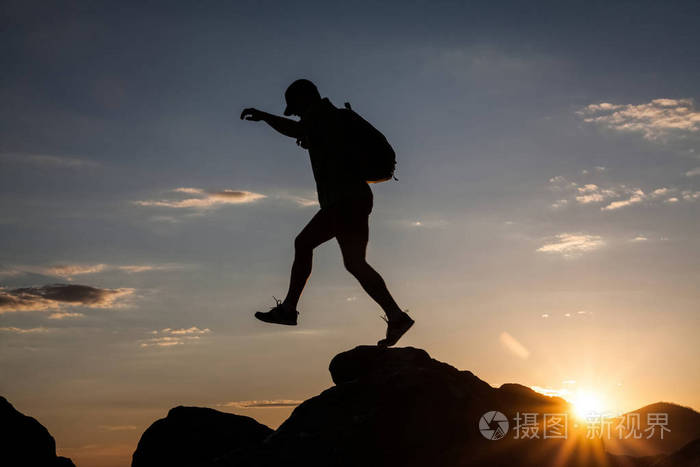 夕阳下登山者徒步旅行的剪影.自由,风险,挑战,成功理念