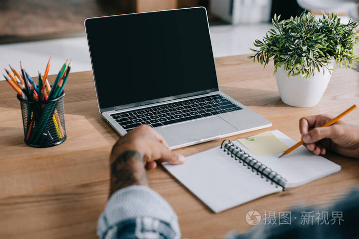 在工作场所用铅笔和笔记本电脑与空白屏幕的人写作的部分观点
