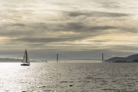 从水面上的小船上看到的旧金山湾多云的夕阳。城市和金门大桥的景色