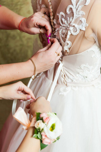 婚礼的概念。新娘的特写礼服的婚纱。服装的紧固过程