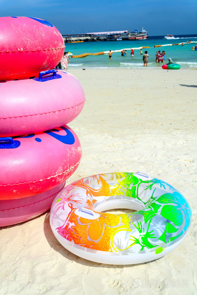 在白色的沙滩上五颜六色的游泳圈