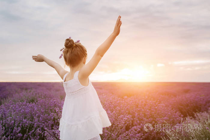 快乐可爱的小女孩在薰衣草领域在日落.自由概念