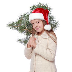 积极的年轻女孩，在圣诞老人的帽子是快乐和欢笑与圣诞树