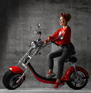 妇女乘坐坐在摩托车摩托车摩托车推迟复古风格笑着笑在红色上衣和牛仔裤