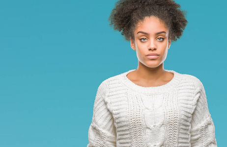 年轻的美国黑人妇女穿着冬季毛衣在孤立的背景下, 面部表情严肃。简单而自然地看着相机
