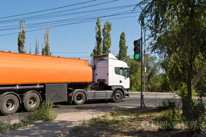 一辆卡车与一辆坦克运输石油产品在工业地区在尘土飞扬的道路上行驶