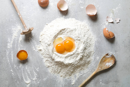 在灰色的桌子上烤面粉和鸡蛋的过程。从上面看