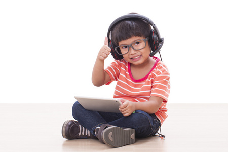 快乐的男孩，戴着耳机连接到一台平板电脑，听音乐